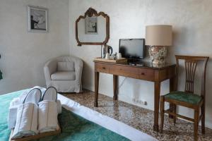 威尼斯罗坎达爱桑蒂阿帕斯托利酒店的一间卧室配有一张桌子、一台电视和一把椅子