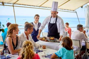 圣玛格利特迪普拉Forte Village Resort - Le Palme的厨师在餐桌上为一群人提供食物