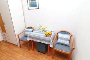 斯拉诺Guest House Franica & Pero Lobrovic的一张桌子,上面有两把椅子和一碗水果