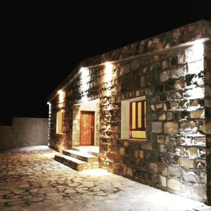 Al HūbJabal Shams Mountain Rest House的石头建筑,晚上有红色的门