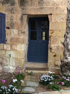 MġarrTa Skorba Farmhouse Mgarr的石头建筑中一扇花朵 ⁇ 的蓝色门