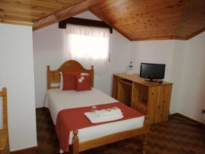 韦拉斯Residência Livramento的一间卧室配有一张床,并在一间客房内配有电视。