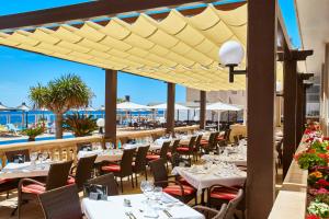 科洛尼亚圣霍尔迪浪漫环球酒店的餐厅设有桌椅,以大海为背景