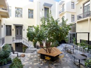 雅典雅典酒店的庭院里种着树,配有桌椅