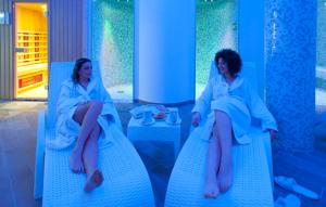 孔图尔西泰尔门卡帕索酒店的两个女人坐在蓝色椅子上