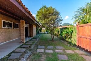 乌巴图巴BEST HOUSES 4: CASA COM PISCINA NA PRAIA GRANDE的一座带栅栏和树的房屋的庭院