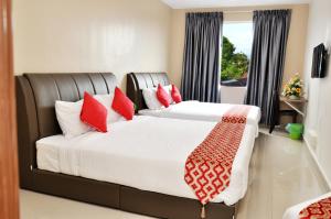 劳勿Hotel Raub Agro的一间卧室配有两张带红色枕头的床