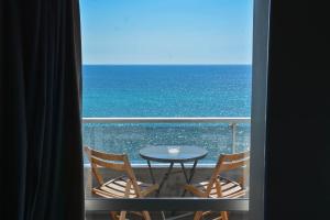 比雷埃夫斯天蝎座海滨酒店的阳台享有海景,配有桌椅。