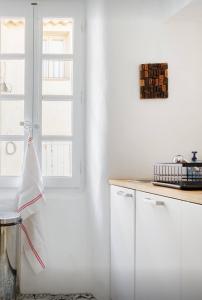 卢马罕Nuits étoilées Lourmarin的厨房配有白色橱柜和窗户。