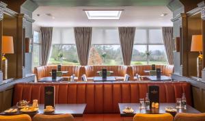 穆林加尔Bloomfield House Hotel, Leisure Club & Spa的餐厅设有棕色皮革座椅和大窗户