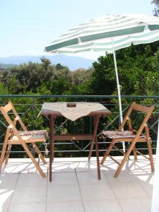 尼基亚娜加丽尼别墅公寓的阳台配有一张桌子和两把椅子以及一把遮阳伞。