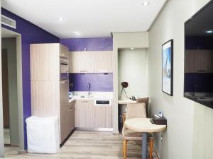卡萨布兰卡勒22公寓式酒店的厨房拥有紫色的墙壁,配有桌子和桌椅