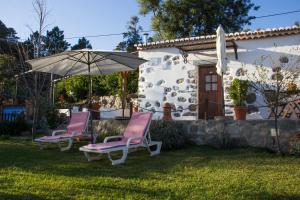 蒙希克Quinta do Tempo Turismo Rural的两把椅子和一把伞在房子前面