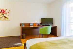 魏森多夫ACANTUS Hotel的酒店客房配有一张床和一张书桌及一台电视