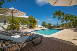圣马丁岛VILLA SAPHIR的一座带游泳池和遮阳伞的别墅
