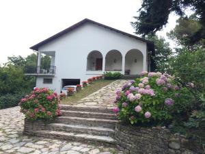 日科德尔格尔福迪艾斯Casa del Sole, Villa indipendente isolata in area verde perfetta smart-working的白色的房子,前面有楼梯和鲜花