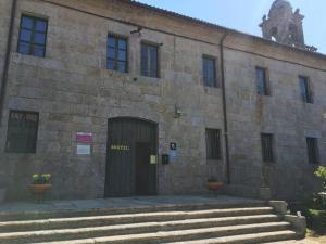 图伊Albergue Convento Del Camino的一座古老的石头建筑,设有门和楼梯