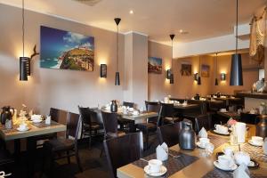 汉堡Hotel Hafentor的餐厅设有桌椅,墙上挂有绘画作品