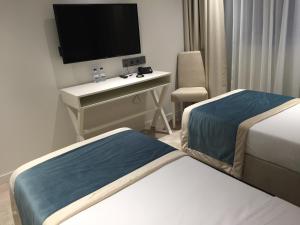 萨兰HOTEL LES 3 VALLÉES的酒店客房设有两张床和一张书桌及电视