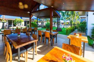 奈扬海滩Phuket Airport Hotel - SHA Extra Plus的一间带木桌椅的餐厅和一个花园