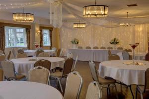 兰戈伦Wild Pheasant Hotel & Spa的宴会厅配有白色的桌椅