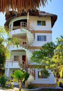 瓦塔穆Simba House的白色的建筑,设有楼梯和茅草屋顶