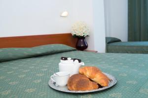圣乔瓦尼·罗通多阿尔伯格侯爵别墅酒店的床上的盘子,上面放着咖啡和羊角面包