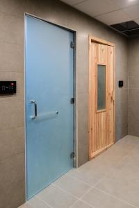 麦纳麦Noor Amwaj Hotel & Apartment的一间铺有瓷砖地板的客房内的大扇蓝色门