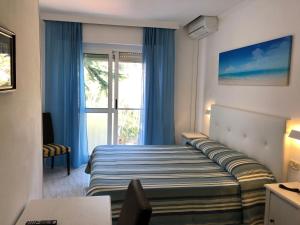 吉廖港Hotel Bahamas的一间卧室配有一张带蓝色窗帘的床和一扇窗户