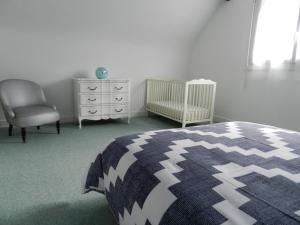 滨海圣洛朗La Maison Blanche的一间卧室配有一张床、一把椅子和一张婴儿床