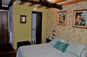 蓬特德乌梅Casa Apilladeira的卧室配有一张床,墙上挂有绘画作品