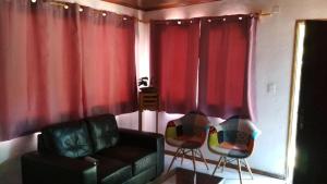新帕尔米拉Casa La Norma的客厅配有红色窗帘、沙发和椅子