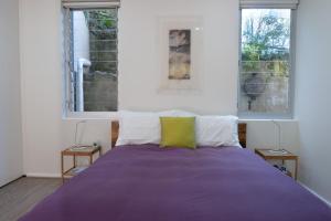 悉尼Bondi Lock-Down Retreat, The Cute Place To Put Up Your Feet的一间卧室配有一张紫色床和两个窗户
