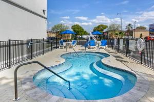 坦帕Sleep Inn & Suites Tampa South的一个带蓝色椅子和围栏的小游泳池