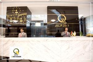 纳杰夫Qasr AlDur Hotel的两个穿着西装的人站在商店柜台后面