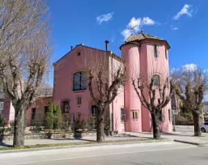 TonaTorre de la Ferrería的一座粉红色的建筑,塔楼旁边树木