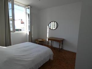 比亚里茨Maison Basque的一间卧室配有一张床、一张桌子和一个窗户。