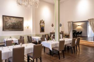 戈斯拉尔艾尔特萌思罗曼蒂克酒店的一间配备有白色桌椅和吊灯的餐厅