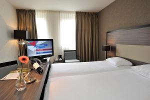 韦尔特Fletcher Hotel-Restaurant Weert的酒店客房设有两张床和一台平面电视。