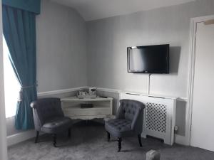 鲍内斯温德米尔纽霍班克旅馆的一间设有两把椅子和一台墙上的电视的房间