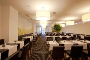 美因河畔法兰克福法兰克福瑞拉科萨酒店总店（高级）的用餐室配有桌椅和灯光