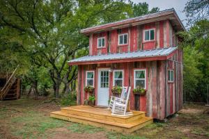 韦科Cozy Cabin Little Red Hen 12 min to Magnolia的红色的小房子,设有门廊和椅子