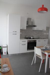 奥列纳Gli olivi的厨房配有白色橱柜、桌子和桌椅