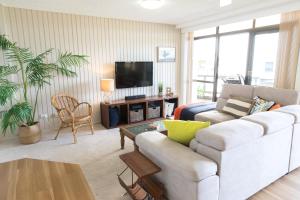 麦夸里港Beauty at the Beach - modern beachfront apartment的客厅配有白色沙发和电视