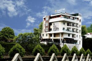 瓦拉纳西Comfort Inn Benares的前面有树木的白色建筑