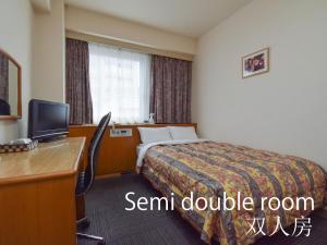冈山玛丽亚酒店的酒店客房配有一张床、一张书桌和一台电视。