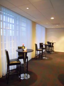 凯尔克拉Fletcher Hotel-Restaurant Parkstad- Zuid Limburg的一间设有桌椅和窗帘的等候室