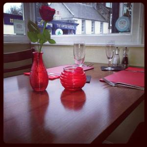 阿伯道尔Aberdour Hotel, Stables Rooms & Beer Garden的木桌边的两只红色花瓶