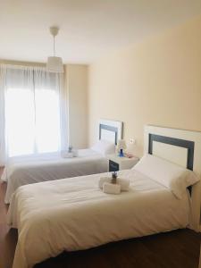 萨拉曼卡Apartamento Puente Romano Portal 4 1-B的一间卧室设有两张带白色床单的床和窗户。