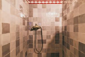 马拉加El Riad Andaluz的浴室铺有棕色和白色瓷砖,设有淋浴。